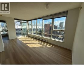 A room with wooden floors and large windows overlooking a cityscape.