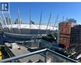 A large stadium with a glass facade building in the background.