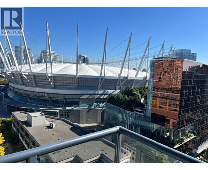 A large stadium with a glass facade building in the background.
