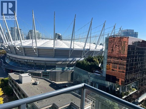A large stadium with a glass facade building in the background.
