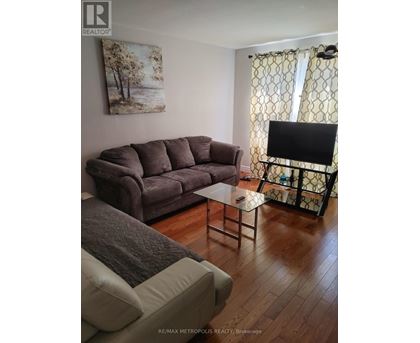 A living room with a grey couch and a painting on the wall.