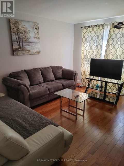 A living room with a grey couch and a painting on the wall.