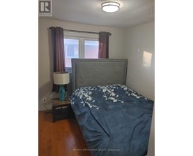 A bedroom with a bed, nightstand and lamp.