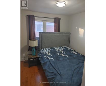 A bedroom with a bed, nightstand and lamp.