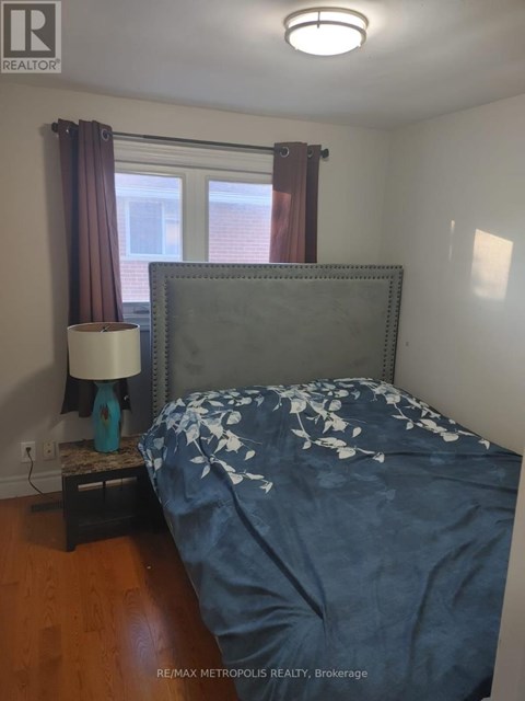 A bedroom with a bed, nightstand and lamp.