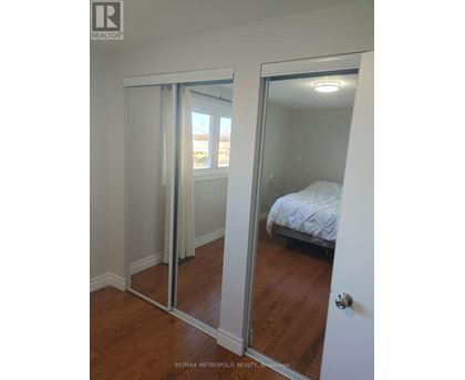 A bedroom with a bed and a mirrored door.