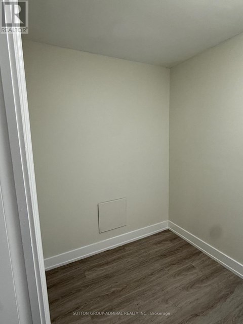 A room with wood flooring and a white wall with a hole in it.