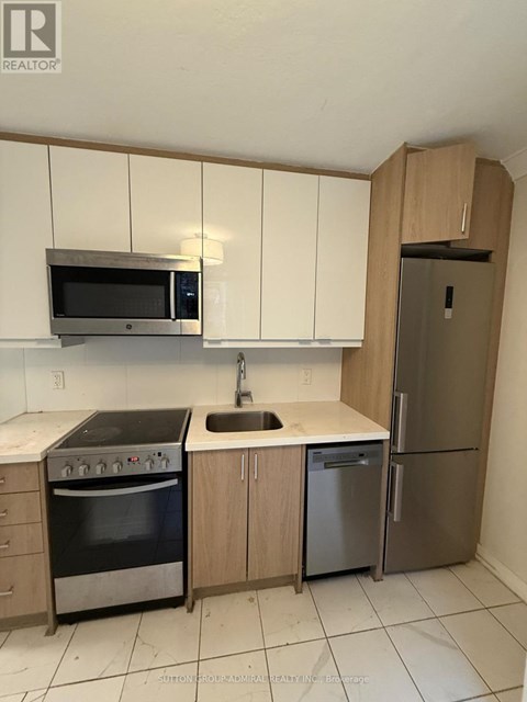 A kitchen with a microwave, oven, sink and refrigerator.