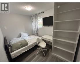 A bedroom with a bed, chair, and shelves.