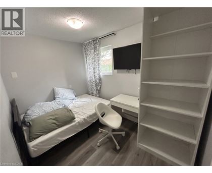 A bedroom with a bed, chair, and shelves.