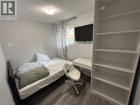 A bedroom with a bed, chair, and shelves.