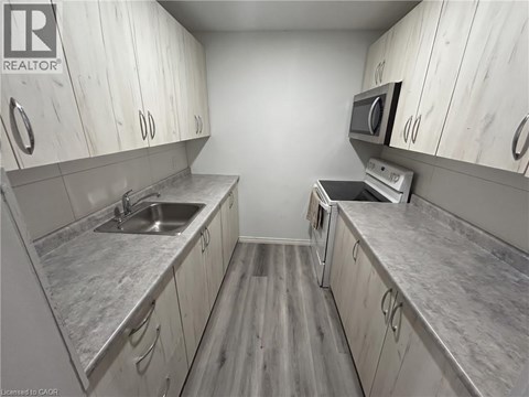 A kitchen with white cabinets and a grey counter top.