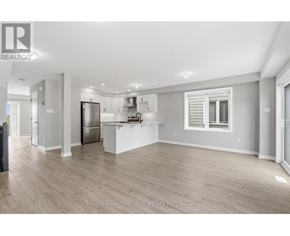A spacious kitchen with white cabinets and a refrigerator.