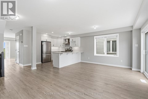 A spacious kitchen with white cabinets and a refrigerator.