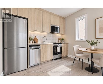 A modern kitchen with a refrigerator, microwave, oven, and sink.