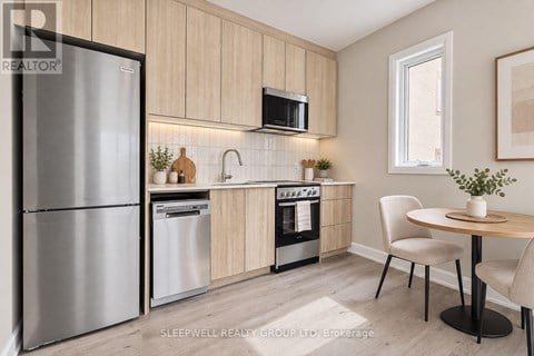 A modern kitchen with a refrigerator, microwave, oven, and sink.