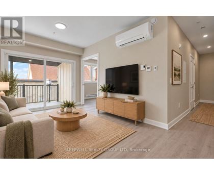 A living room with a couch, a coffee table, and a flat-screen TV mounted on the wall.