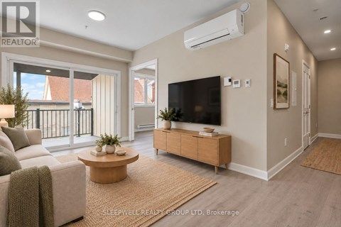 A living room with a couch, a coffee table, and a flat-screen TV mounted on the wall.