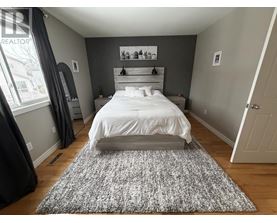 A bedroom with a large bed and a grey rug.