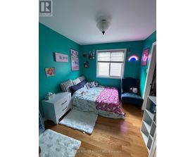 A bedroom with a bed, nightstand, and a window.