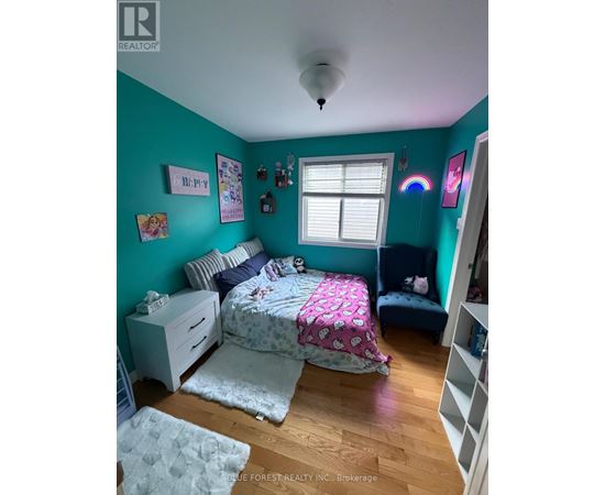 A bedroom with a bed, nightstand, and a window.
