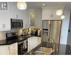 A kitchen with white cabinets and a black counter top.