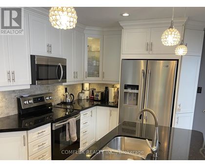 A kitchen with white cabinets and a black counter top.