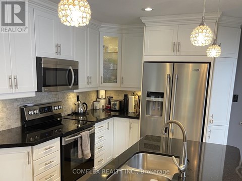 A kitchen with white cabinets and a black counter top.