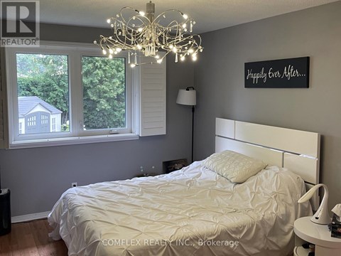 A bedroom with a white bed and a chandelier.