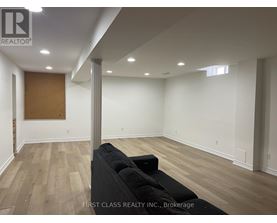 A room with a black couch and wooden flooring.