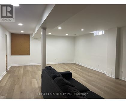 A room with a black couch and wooden flooring.