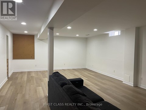 A room with a black couch and wooden flooring.