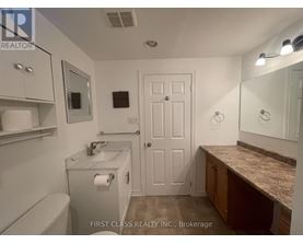 A bathroom with a toilet, sink, mirror, and medicine cabinet.