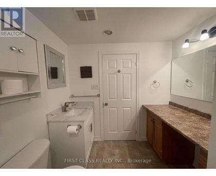 A bathroom with a toilet, sink, mirror, and medicine cabinet.