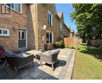 A sunny day at a brick house with a patio and a wicker chair.