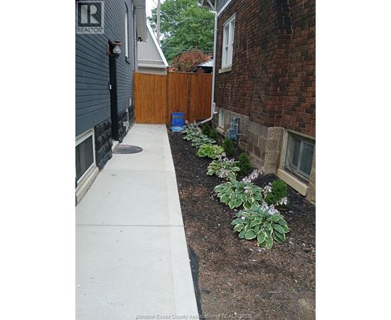 A small garden with a white pathway and a blue barrel.