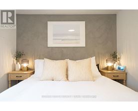 A bedroom with a large bed, two nightstands with lamps, and a framed picture on the wall.