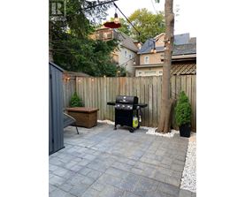 A BBQ grill is on a patio with a table and chairs.