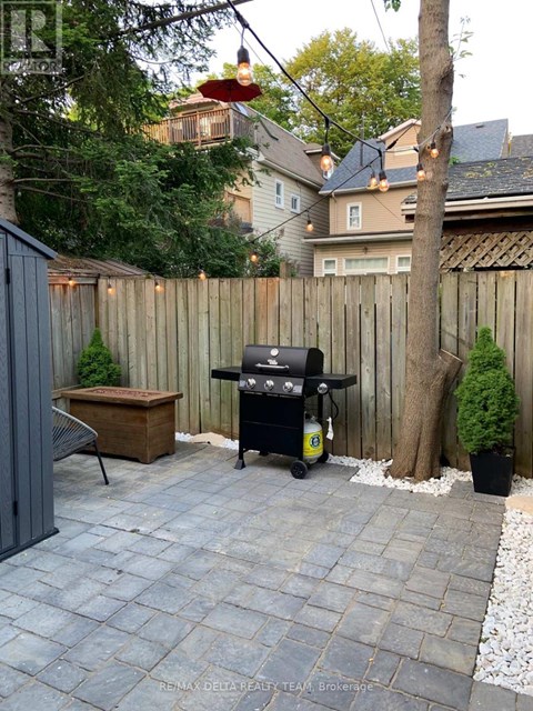 A BBQ grill is on a patio with a table and chairs.