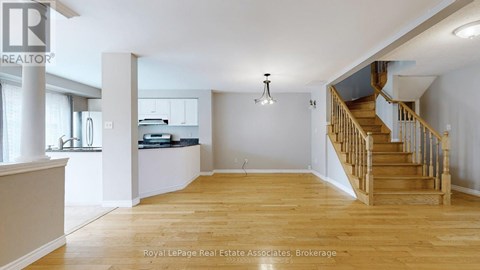 A spacious room with wooden floors and a staircase leading to another level.