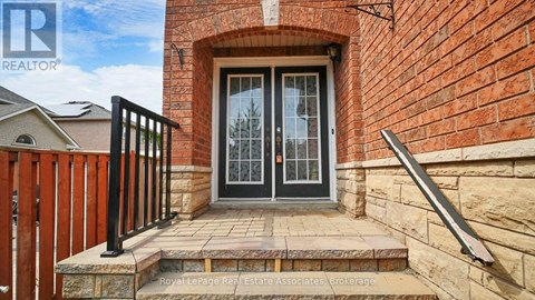 A house entrance with a black gate and a brick wall.