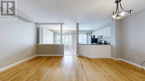 A spacious room with wooden flooring and a large window.