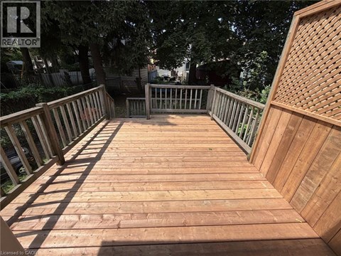 A wooden deck with a railing and a tree in the background.