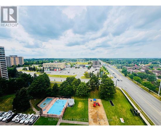 A bird's eye view of a swimming pool surrounded by a grassy area and a parking lot.