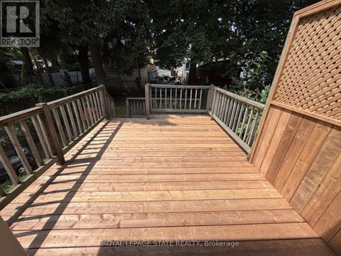 A wooden deck with a railing and a tree in the background.