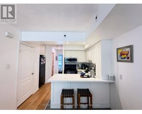 A kitchen with white cabinets and a white island with two stools.