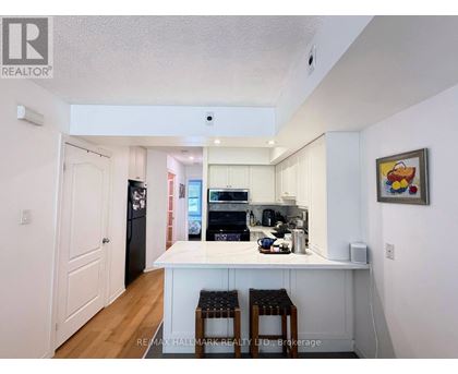 A kitchen with white cabinets and a white island with two stools.
