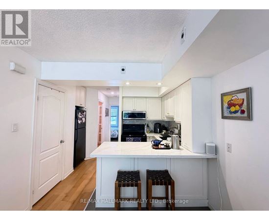 A kitchen with white cabinets and a white island with two stools.