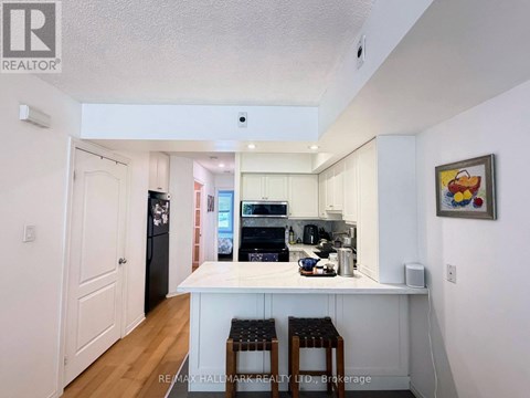 A kitchen with white cabinets and a white island with two stools.