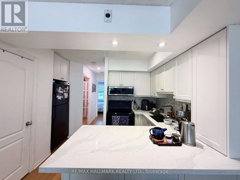 A kitchen with white cabinets and a marble countertop.